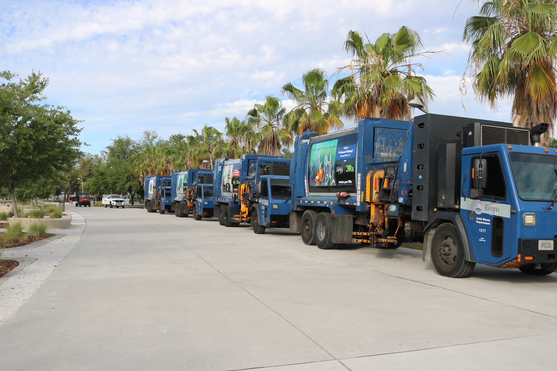 Four blue Tampa recycling trucks with artwork on the side.