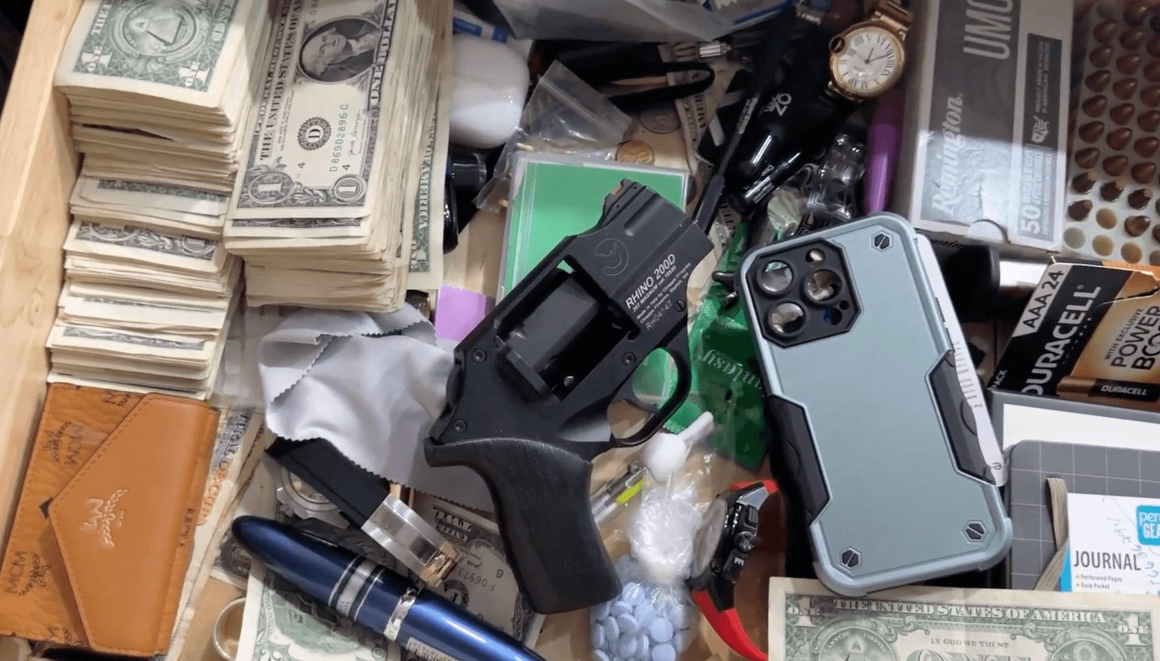 money, gun, phone, pills and other stuff in a box
