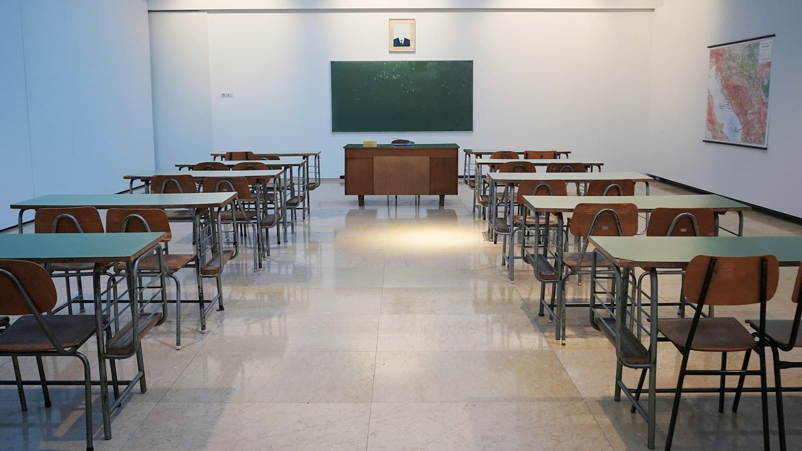 Empty elementary classroom with rows of desks facing a chalkboard