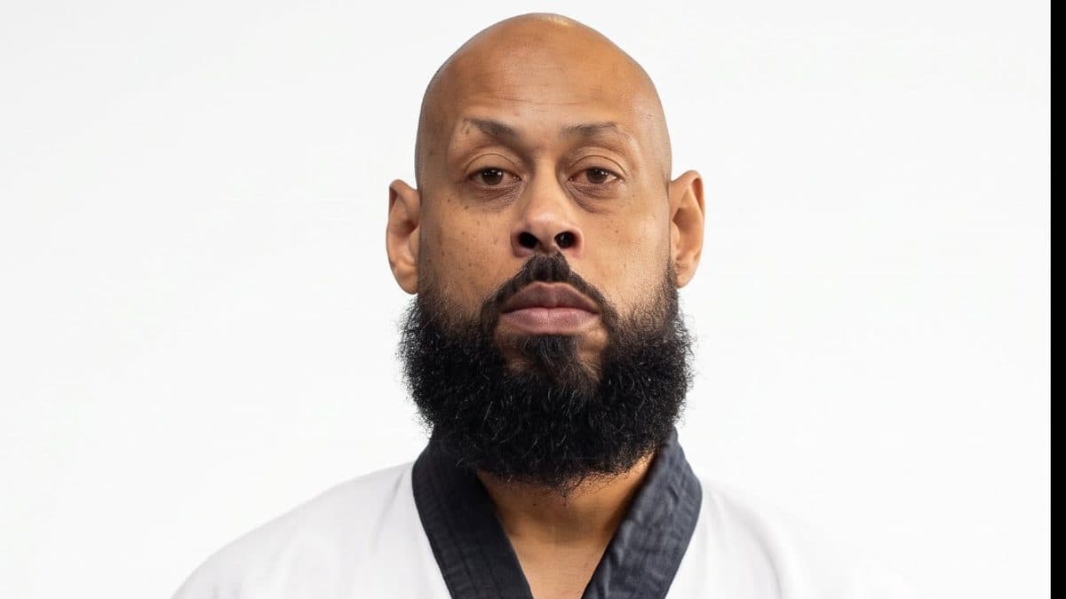 A portrait of Kyo Sa Nim Odell Johnson wearing a traditional white Tang Soo Do martial arts uniform (Dobak) with a black belt