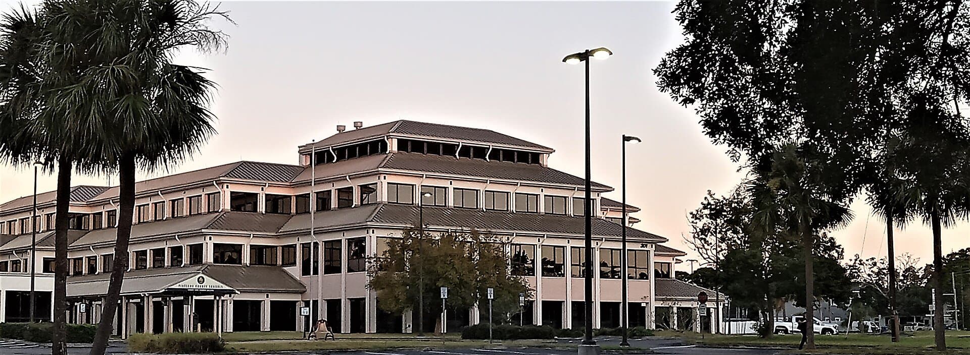 The Pinellas County School Board building in Largo at dusk, framed by palm trees